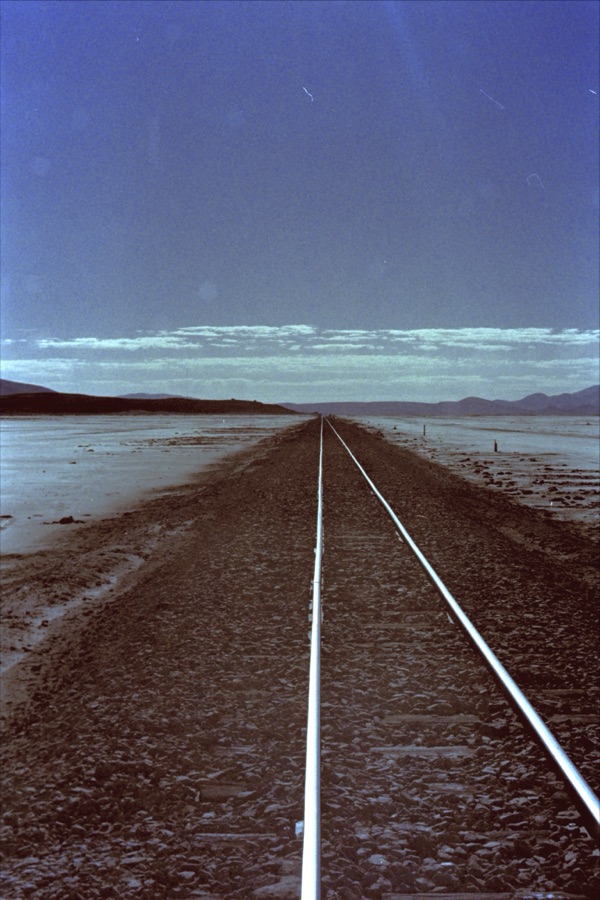 A single railway track running dead straight into the horizon across the altiplano