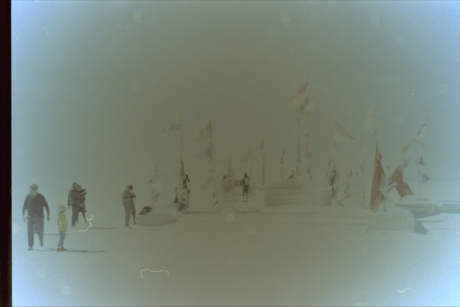Visitors among rows of national flags on the Uyuni salt flat, bleached almost white