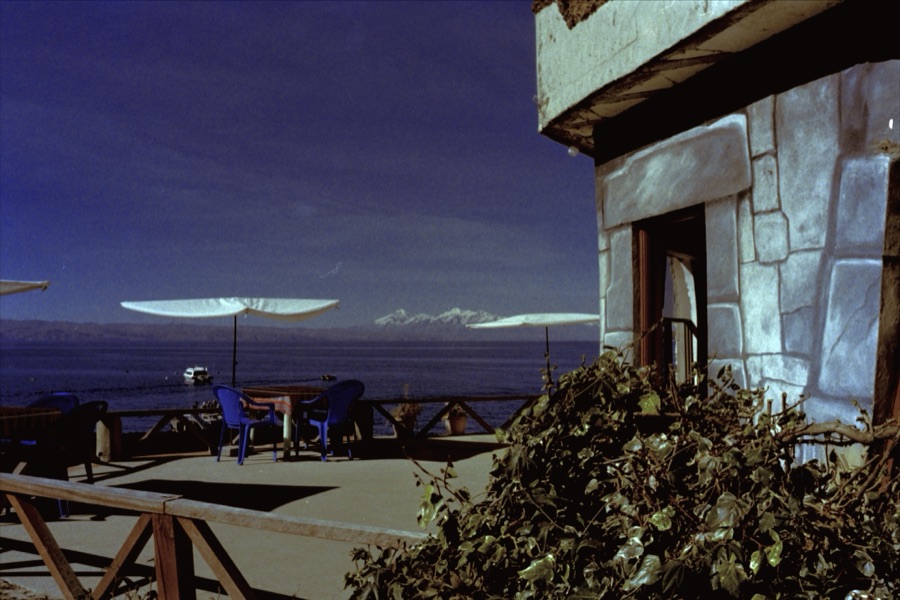 Sun umbrellas on a terrace above Lake Titicaca with a snow range on the far shore